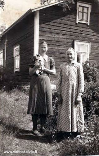 Aili ja Selma Kykyri Sahamäellä
Kuvassa ovat Aili (1901-1957) ja äitinsä Selma Kykyri (1873-1947) talonsa edustalla Sahamäellä (Kykyri 28).  Kuvaan on päässyt myös Ailin sylissä oleva puna-musta-valkoisen kirjava kissa nimeltään Räpäkkä.  Kuva on 1940-luvun puolivälistä.    
Keywords: Kykyri Sahamäki