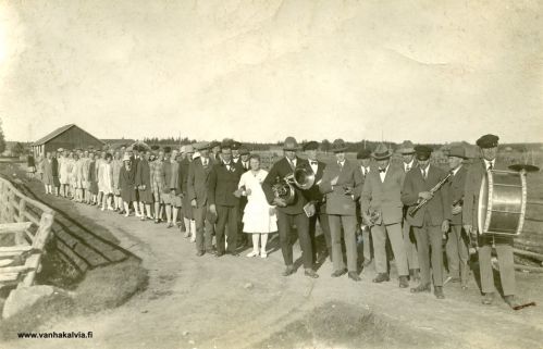 Hääkulkue 2.9.1928
Hääpari Viljami Leppiniemi ("Leppi-Ville", Leppiniemi 5) ja Tyyne Järvinen (Pihlajakangas 2).
Sulhasen takana vasemmalla Juho Ruokoja (Ruokoja 24). "Morsian haettiin Ruokojasta, vaikka asuivat kirkonkylällä." "Juho Ruokoja oli toiminut Leppi-Villen puhemiehenä." Kuvassa etualalla Kälviän suojeluskunnan torvisoittokunta.

Keywords: Leppiniemi Pihlajakangas Järvinen Ruokoja 