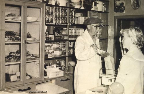 Sulon K-kaupassa
Kuva Ruotsalolta, Sulo Hakuntin kaupasta. 
Kuvassa kauppias Sulo (s. 1912) sekä asiakkana Anni Hakunti, ja pieni poika edessä on Erkki Valkama. Kuva on otettu 1950-luvun puolenvälin jälkeen. 
Kauppa sijaitsi nuorisoseurantalon risteyksestä hieman koululle päin, nykyisen Porkonjärventien varressa. Rakennus on paikoillaan, mutta muussa käytössä.
Keywords: Hakunti