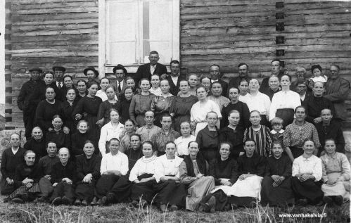 Välikylän äitienpäiväjuhlat 1923
Välikylän koululla keväällä 1923 otettuun äitienpäiväkuvaan ovat myös miehet päässeet mukaan. Useimmat henkilöt ovat vielä tunnistamatta. Toisen rivin oikeanpuoleisessa päässä istuu Vilhelmiina Huhta (s. Hakunti, Huhta 18) ja valkopukuinen nainen kolmannessa rivissä alhaalta kuvan keskellä hieman oikealla on Välikylän koulun opettaja Aili Järvi (Järvi 24).  Alarivi toinen oik. Eedla Haapasalo, neljäs Sofia Rautomäki (os. Hilli), viides oik. Lyyti Palo. Alarivi neljäs vas. Mari Pajala (os. Maunula). Toinen rivi ensimm. vas. Sofia Kotka (os. Hilli, Saivarheen torpasta). Toinen rivi oik. neljäs Lydia Ruokoja (Ollin Lyyti). Toinen naisten rivi ylh. ensimm. vas. Hanna Tuomisalo, neljäs vas. Lempi Ruokoja (os.Nissi). Opettaja Aili Järven yläp.vas. Kustin Hanna eli Hanna Aho Huhtan mäkituvasta. 
Keywords: Huhta Järvi Haapasalo Rautomäki Palo Pajala Kotka Ruokoja Tuomisalo Aho