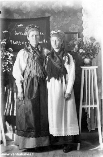 Nasto ja Maria Laine juhla-asuissa
Vuokkiniemessä syntyneet Nasto (vas.) ja Maria Laine. Kälviälle vuonna 1920 asettuneiden vienalaislaukkureiden Pekka ja Mikko Laineen rouvat Vienan naisen juhlapuvuissa. Taustalla näkyvässä seinävaatteessa lukee: "Sortumatta souda, vaikk´ ois vastatuulta". 
Keywords: Laine 