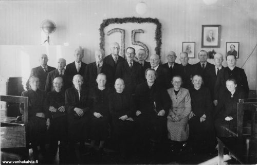 Kirkonkylän koulun 75-vuotisjuhlaväkeä
Takarivi vas. lähtien: Tunnistamaton, Miika Maajärvi (maanviljelijä Lukkarinmäeltä, Pernu 41), Toivo Siirilä (opettaja, Rajamäki, tunnistajan isä, Siirilä 18), Otto Koskela (palasi ennen talvisotaa Amerikasta, asui omassa talossa Lampinkankaalla, Koskela 16), Valfrid Raitala (Saxell 2), Otto Tuunala, Oskari Siirilä (maanviljelijä Siirilän Nikkarintuvasta, Siirilä 20), Verner Maunumäki (Maunumäki 32), mahdollisesti Aatu Tuunala (pankinjohtaja, Tuunala 27), "Aari" Adrian Lähdevirta, posteljooni (Nuottila 5), Antti Vähähyyppä (Vähähyyppä 12), Jalmari Pernu (maanviljelijä Suutarinmäeltä, Pernu 38) ja oikealla Sisko Siirilä (tunnistajan isän nuorin sisko, asui Siirilän taloa, Siirilä 18).
Eturivi vas. lähtien: tunnistamaton, tunnistamaton, tunnistamaton, tunnistamaton, tunnistamaton, Helmi Pernu ("Lukkarinmäen Helmi", Pernu 41), Lilja Pernu?, Helmi Toivonen?, oikealla Ester Penttilä (Justus Penttilän sisar, Penttilä 27).

Seinällä olevat kuvat: vasemmalla opettaja Juho Siirilä (Siirilä 18), keskellä Suomen kansakoulun isä Uno Cygnaeus ja oikealla opettaja Matti Karhulahti (Karhulahti 25).


