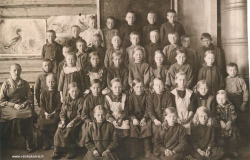 Ruotsalon koululaisia n. 1921
Opettaja Rebekka Ruuska (o.s. Huttula), poika opettajan vieressä Aatto Kippo (s. 1911, Kippo 26). Alarivissä lattialla keskellä Mirja Annikki Kinnari (s. 1913, m. Santapakka, Kinnari 29 Junnila). Alimmaisella penkkirivillä istumassa 3. vas. Vieno Palola (s. 1913, Palola 4) ja oikealla reunalla 3. oikealta mahd. Eila Kerola (s. 1917 ?, Kerola 28).
Ylimmäisessä rivissä oik. Aarne Harju (s. 1912, Harju 21), 2. oikealta mahdollisesti Taimi Hakunti (s. 1911, Hakunti 21) ja Taimin vasemmalla puolella ehkä Toivo Hakunti (s. 1910, Hakunti 22). Takana vasemmalla taulujen edessä seisovat kaksi tummapuseroista poikaa voisivat myös olla Hakunilta, ehkä Toivo ja veljensä Sulo (s. 1912). Varmistusta tietoihin kaivattaisiin vielä. Toinen rivi ylh. 5. oik. Aimo Rimmi (Rimmi 20). Takki päällä uunin vieressä on luultavasti Harjun Hannes (s. 1912, Harju 22), mutta tämä tieto on vielä vähän epävarma.
Keywords: Ruuska Huttula Kinnari Junnila Santapakka Palola Kerola Hakunti Harju Kippo Rimmi