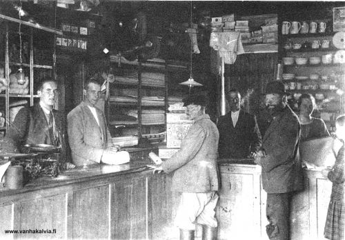 Osuuskaupassa
Asiointia Kälviän Osuuskaupassa kesällä 1923. Tiskin takana palvelevat harjoittelijat Kalervo Honkala (vas.) ja Martti Suonperä. Kassakoneen vieressä kaupanhoitaja Kalle Nissi ja oikealla myyjätär Linda Salo (m. Karjalainen). 
Oikealla oleva pikkutyttö on Lindan sisar Helmi Salo.  Knallipäinen henkilö on "vapaaherra" Antti Heikkilä (Heikkilä 16) ja kolmas asiakas Santeri Pajala.
Keywords: Heikkilä Honkala Suonperä Nissi Salo Karjalainen Pajala 