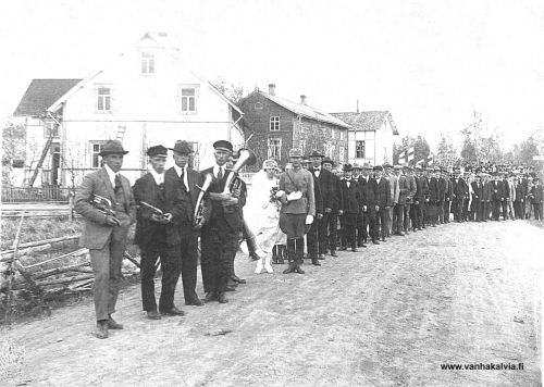 Asujamaan häät
Ilmari Asujamaan (synt. 11.1.1900) ja Meeri Kuusiston häät 8.6.1924. Hääkulkueen taustalla apteekki, KPO ja Tarmon talo. (Asujamaa 18, Honkavaara).
Ilmari Asujamaa toimi Kälviän suojeluskunnan paikallispäällikkönä 1922-32 sekä aluepäällikön sijaisena. Vuonna 1937 Ilmari lähti Australiaan. Asuinpaikkoja siellä olivat Brisbane ja Tully. Työpaikat olivat tupakka- ja sokerifarmeilla. Sodan jälkeen Ilmari Asujamaa toimi lentokonemekaanikkona Darwinissa. Siellä hän kuoli 25.6.1965.

Keywords: Asujamaa Kuusisto Australia Darwin Brisbane Tully