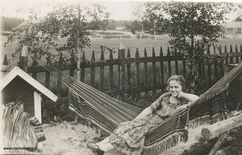 Lepohetki riippumatossa 
Kuva on kauppias Kalle Rahkosen pihalta. Riippumatossa lepäilee kuvan tietojen mukaan Kallen työkaveri, jonka nimi ei ole tiedossa. Kalle Rahkonen (s.1877) tuli vuonna 1912 perheineen Ullavalta Kälviälle ja piti kauppaa Kalle Nissin rakentamassa talossa (entinen Yhtiökauppa). Vuonna 1926 Rahkoset muuttivat Haapajärvelle. (Mattila, Kauppias)
Keywords: Rahkonen Ullava Haapajärvi